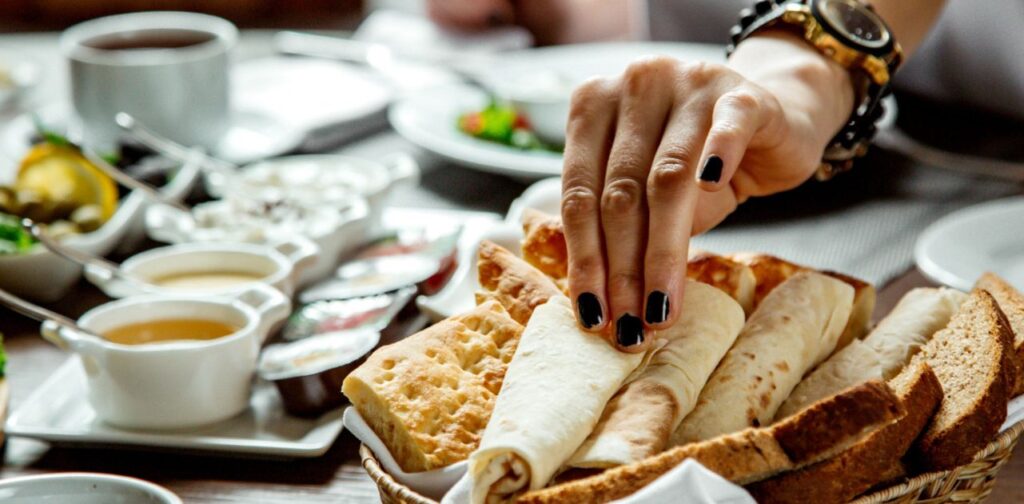 Nainen ottaa leipää herkullisesta brunssipöydästä.